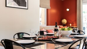 A dining area with a table set for two, a bottle of wine, and a bowl of salad.