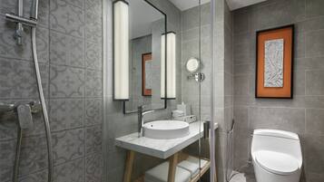 Un baño moderno con ducha envuelta en vidrio, un lavamanos blanco y un inodoro.