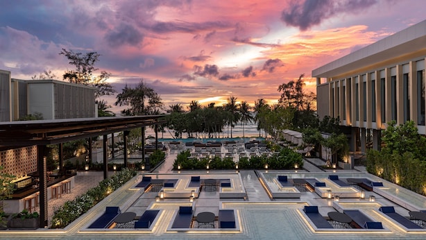 A rooftop pool area with lounge chairs and tables, surrounded by greenery and a modern building. - Four Points by Sheraton Phuket Patong Beach Resort (Patong)