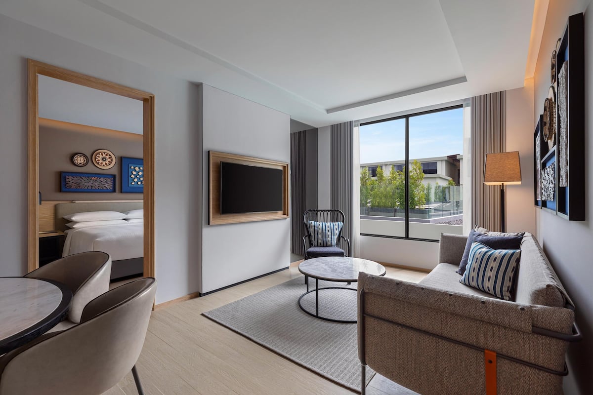 Habitació d'hotel moderna amb llit, televisió, sofà, taula de dinar i cadira.