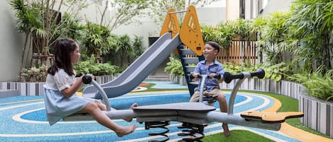 An outdoor exercise area with a slide and a stationary bike.