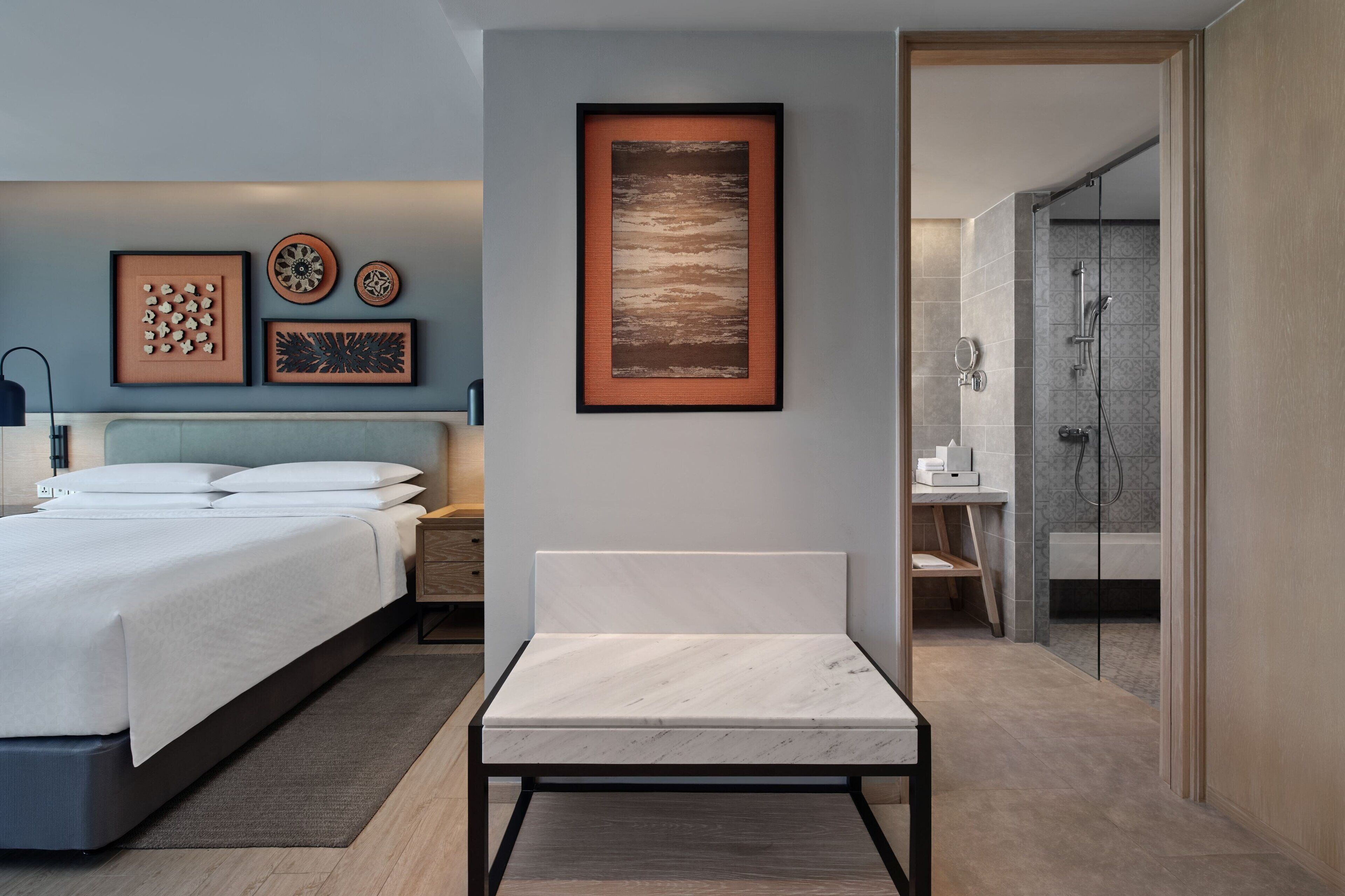 A modern bedroom with a bed, bedside tables, and framed artwork on the wall.