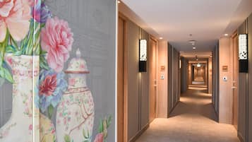 A hotel corridor with wooden doors, a carpeted floor, and wall-mounted light fixtures.