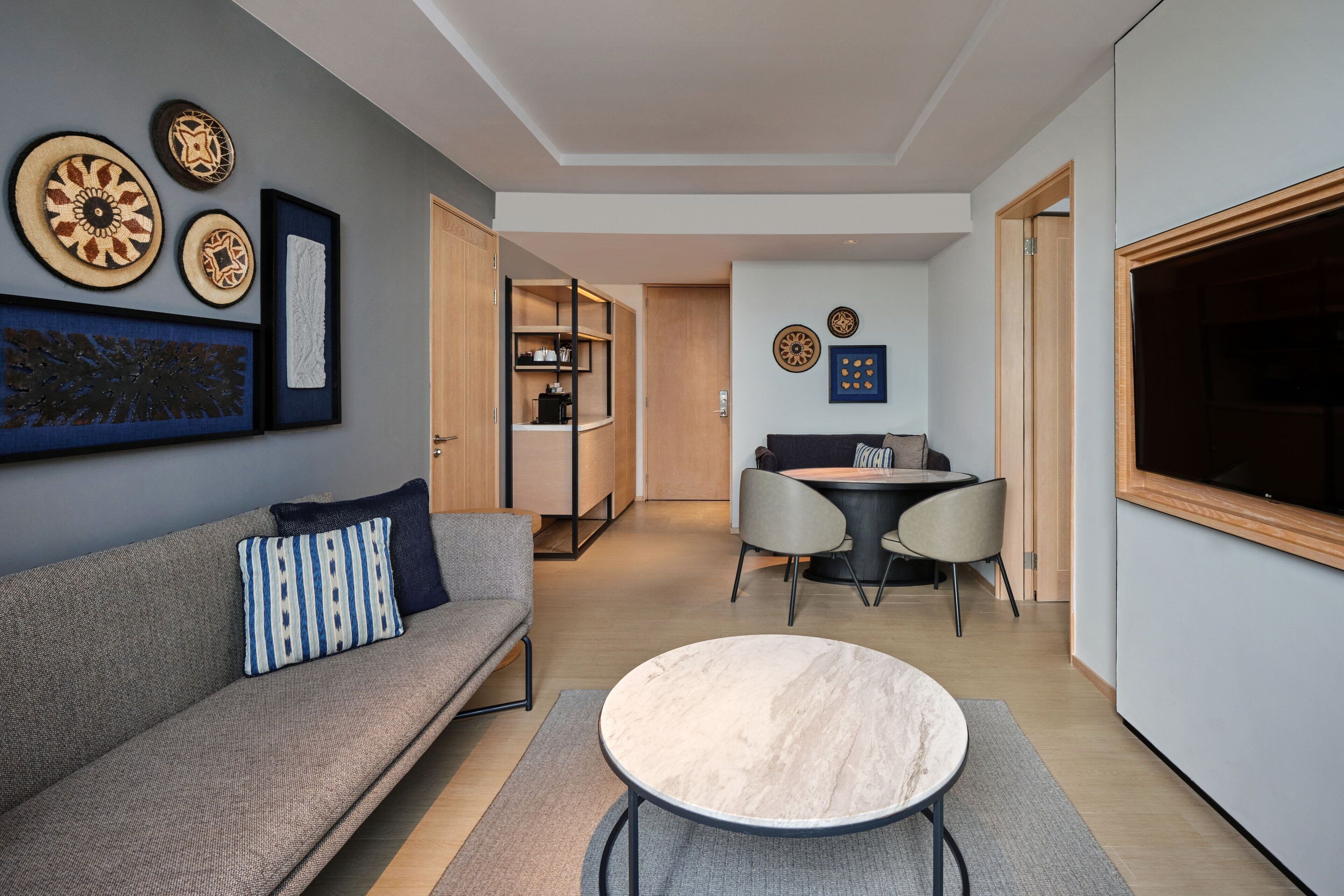 A modern living room with a sofa, a round coffee table, and a dining area with a table and chairs.