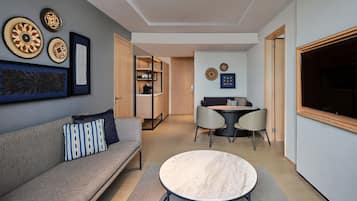 A modern living room with a sofa, a round coffee table, and a dining area with a table and chairs.