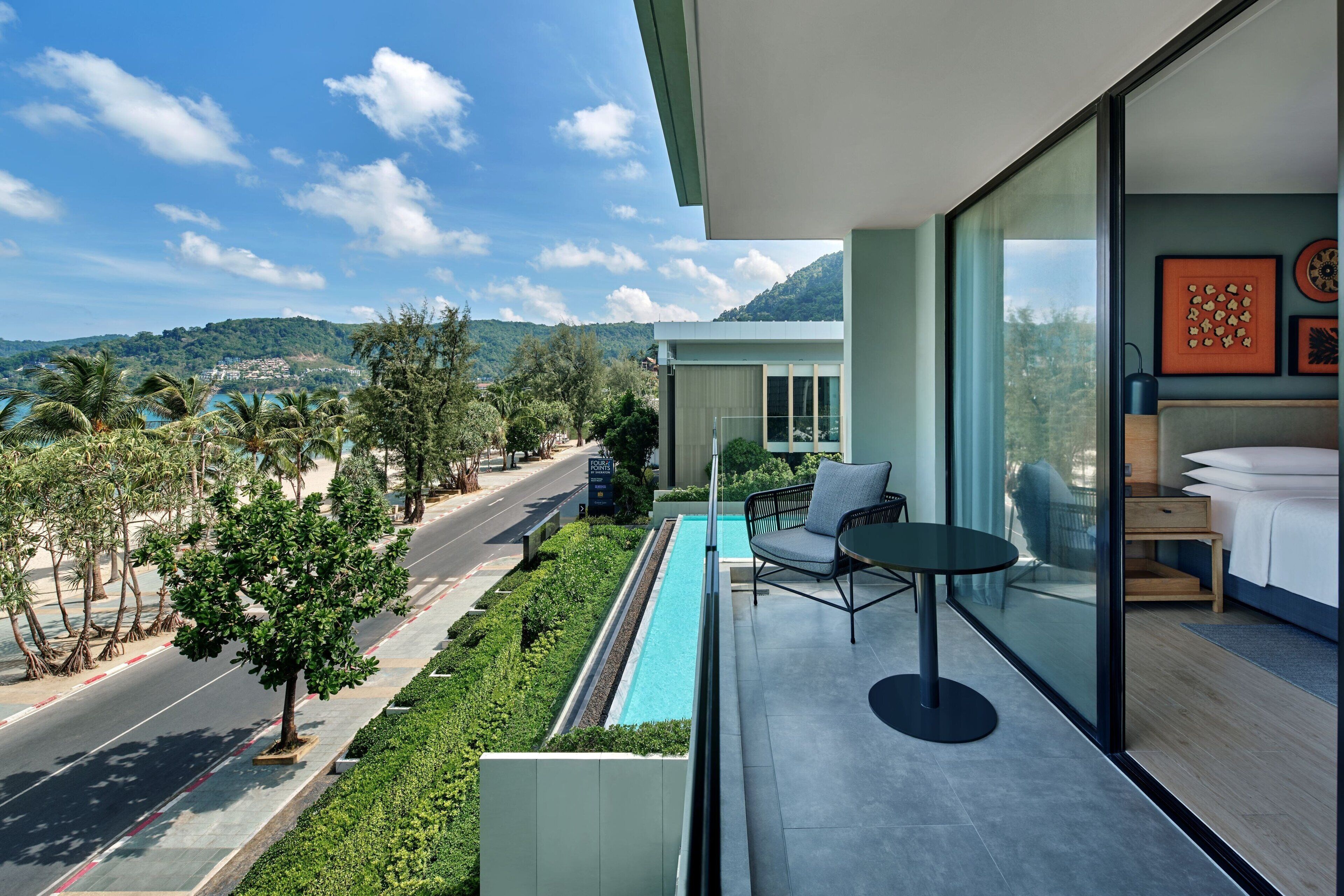 A modern hotel room with a large window, a small pool, and a view of the surrounding landscape.