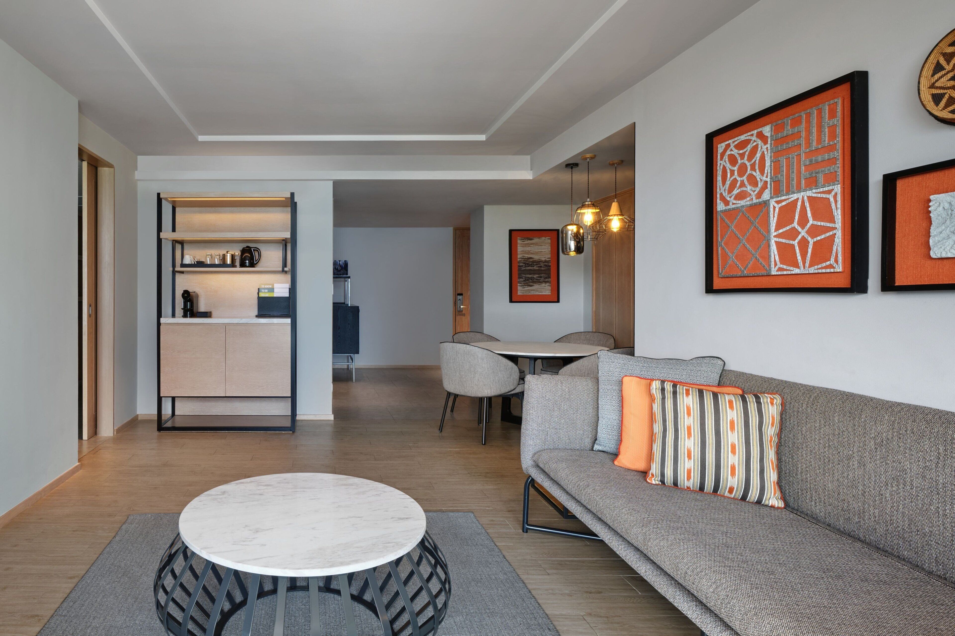 A modern living room with a gray sofa, a round coffee table, and a dining area with a table and chairs.