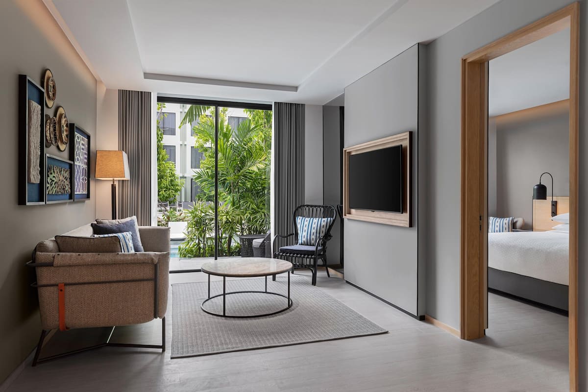 Habitació d'hotel moderna amb sofà, cadira, taula rodona, televisió i llit.