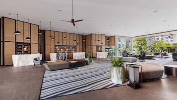 Eine großzügige Lobby mit einer zentralen Sitzecke, einem Empfangsschalter und einem modernen Deckenventilator.