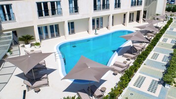 Una piscina al aire libre de temporada, sombrillas