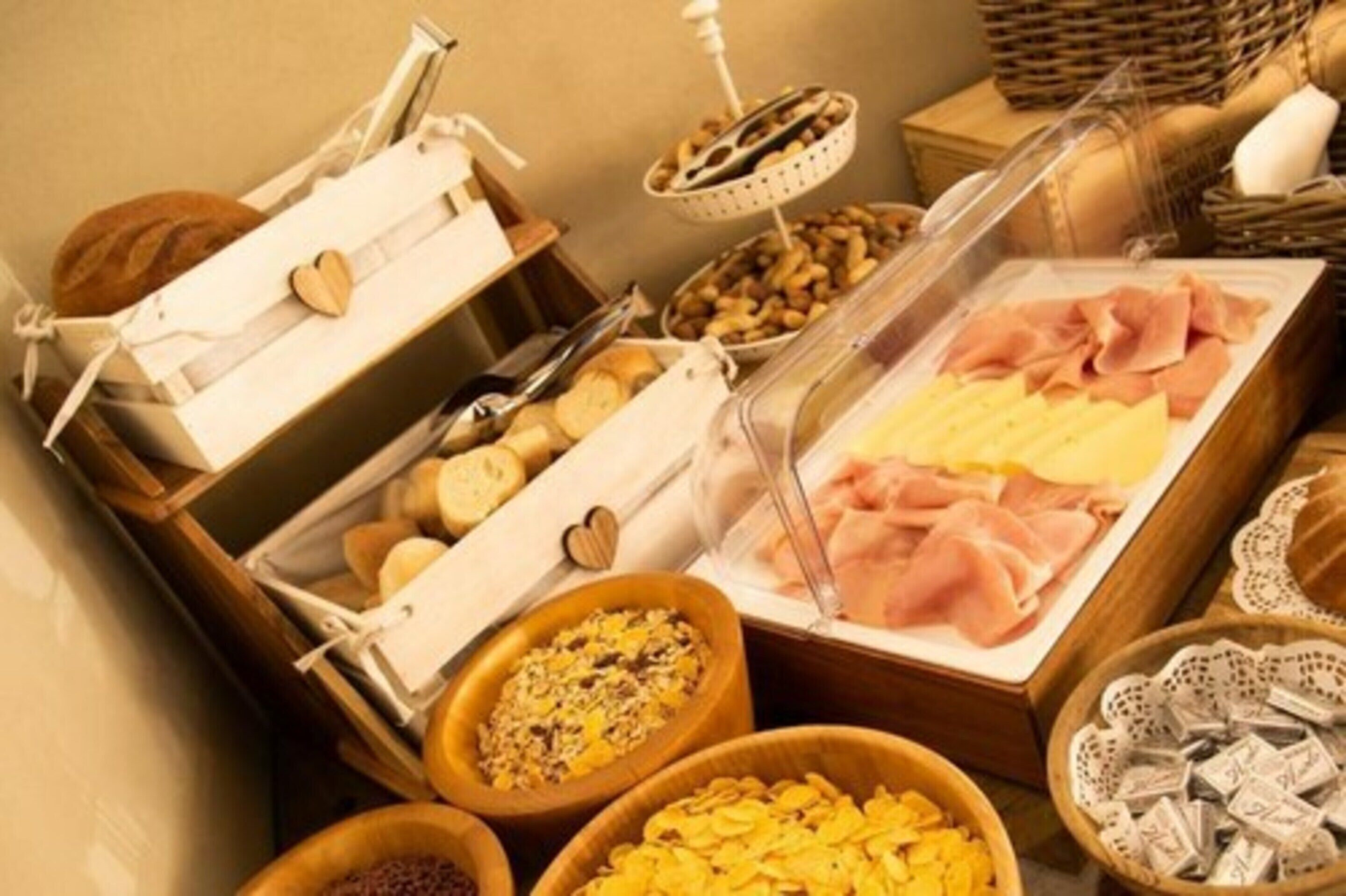 Un buffet con un'ampia scelta di cibi, tra cui carni, formaggi e cereali.