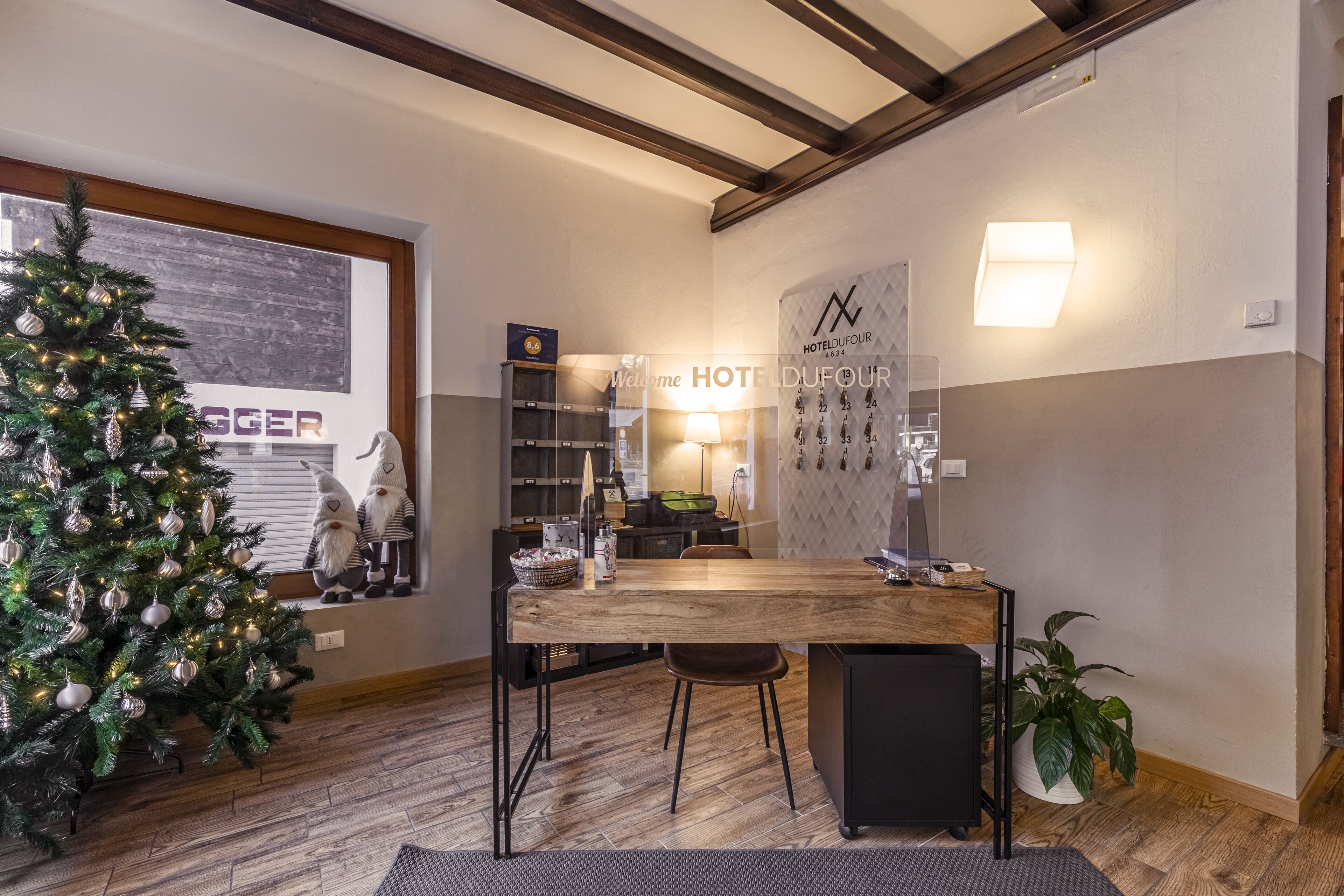 A hotel lobby with a Christmas tree, a reception desk, and a wall-mounted calendar.