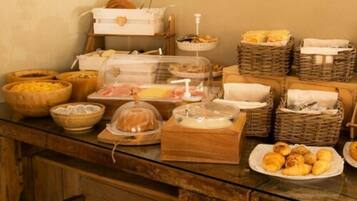 Un buffet proposant une variété de plats, notamment du pain, des pâtisseries, et une vitrine réfrigérée.