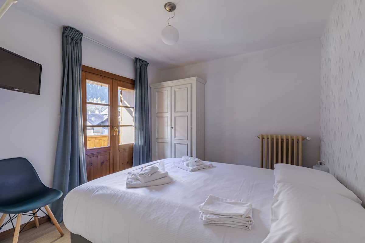 Une chambre avec un grand lit, une chaise, une armoire et un radiateur.