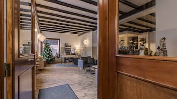 A modern hotel lobby with a wooden floor, a reception desk, and a Christmas tree.