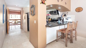 Une cuisine équipée d’un four à micro-ondes, d’une cuisinière et de chaises en bois.