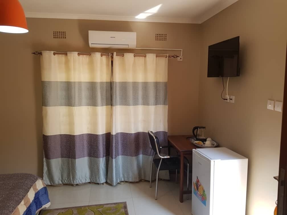A small room with a bed, a desk, a chair, a television, and a refrigerator.