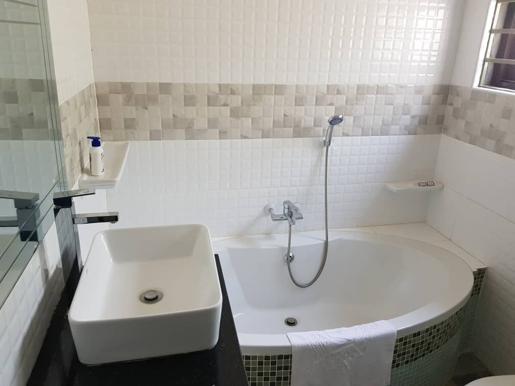 Un baño con lavamanos blanco, bañera y ducha.