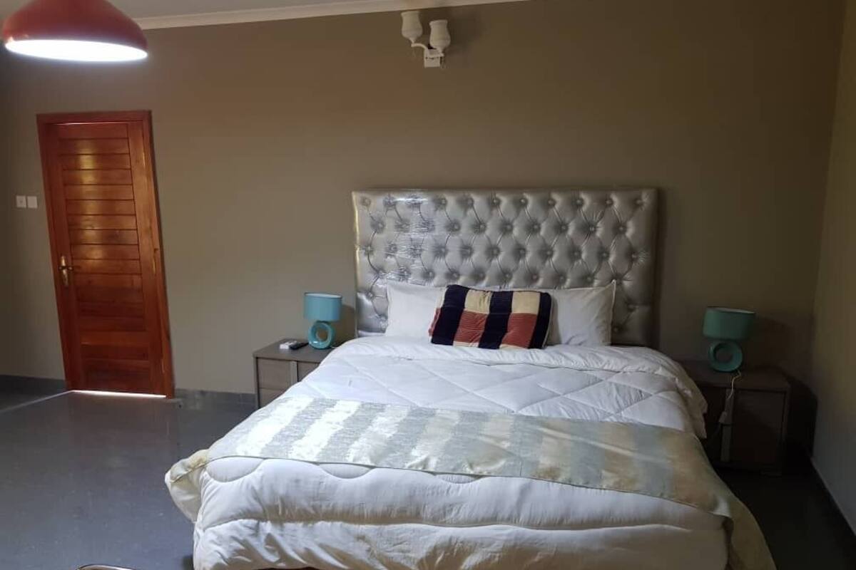 Un dormitorio con una cama grande, una puerta de madera y dos lámparas de noche.