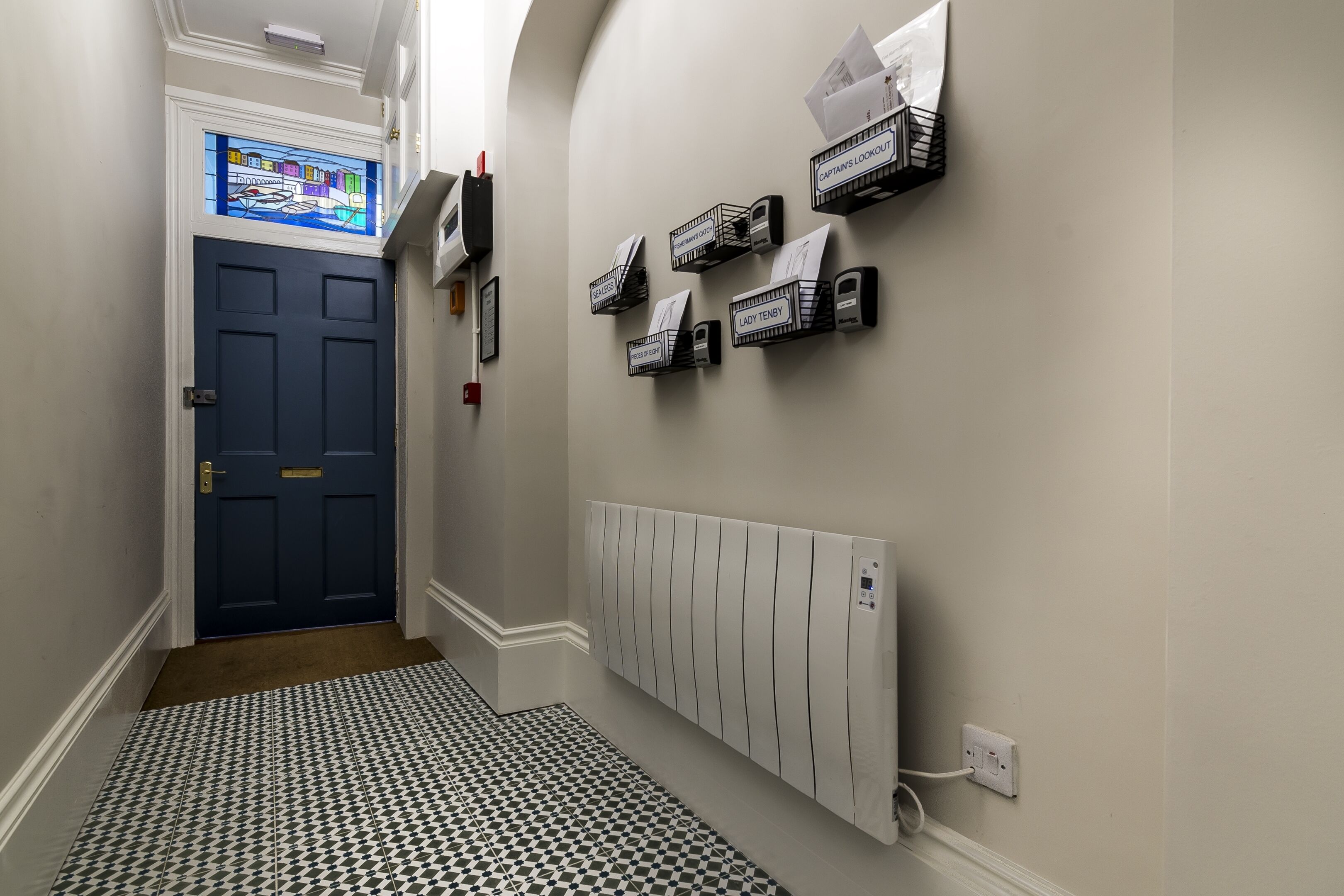 A narrow hallway with a patterned floor, a blue door, and a radiator.