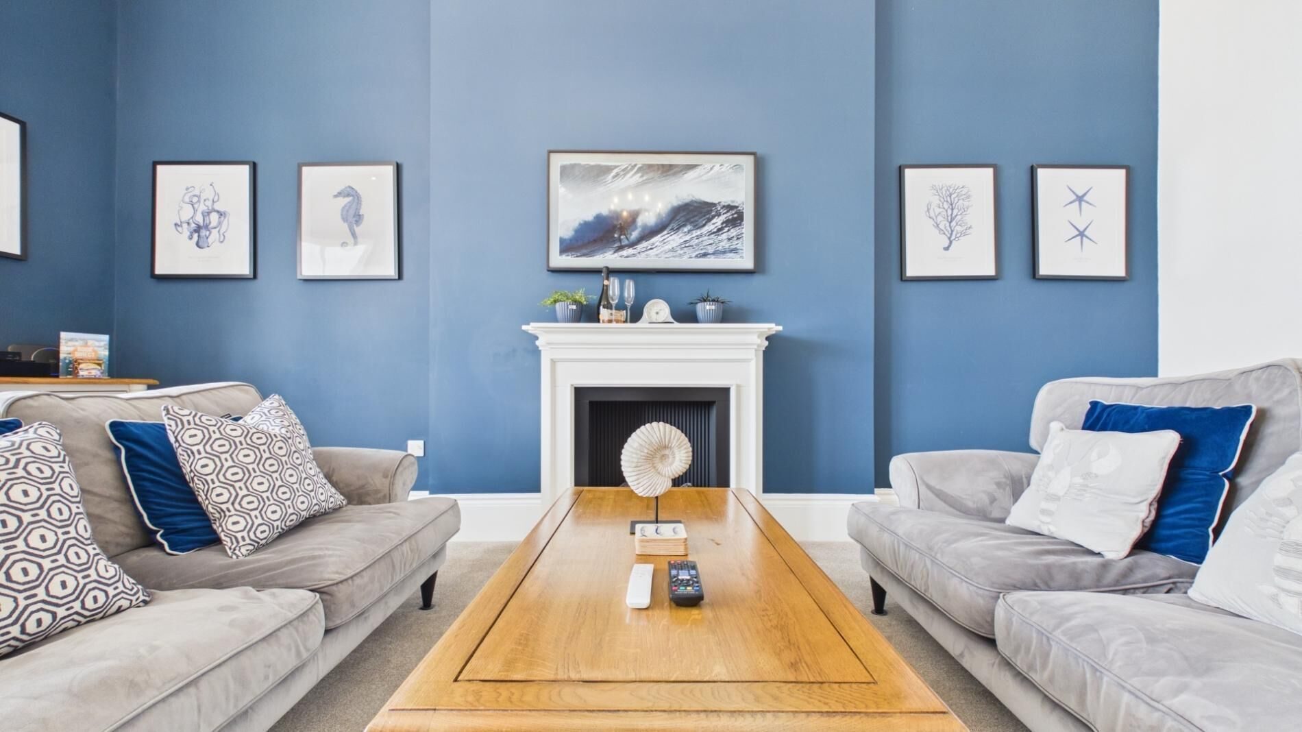 A living room with two sofas, a coffee table, a fireplace, and framed artwork on the walls.