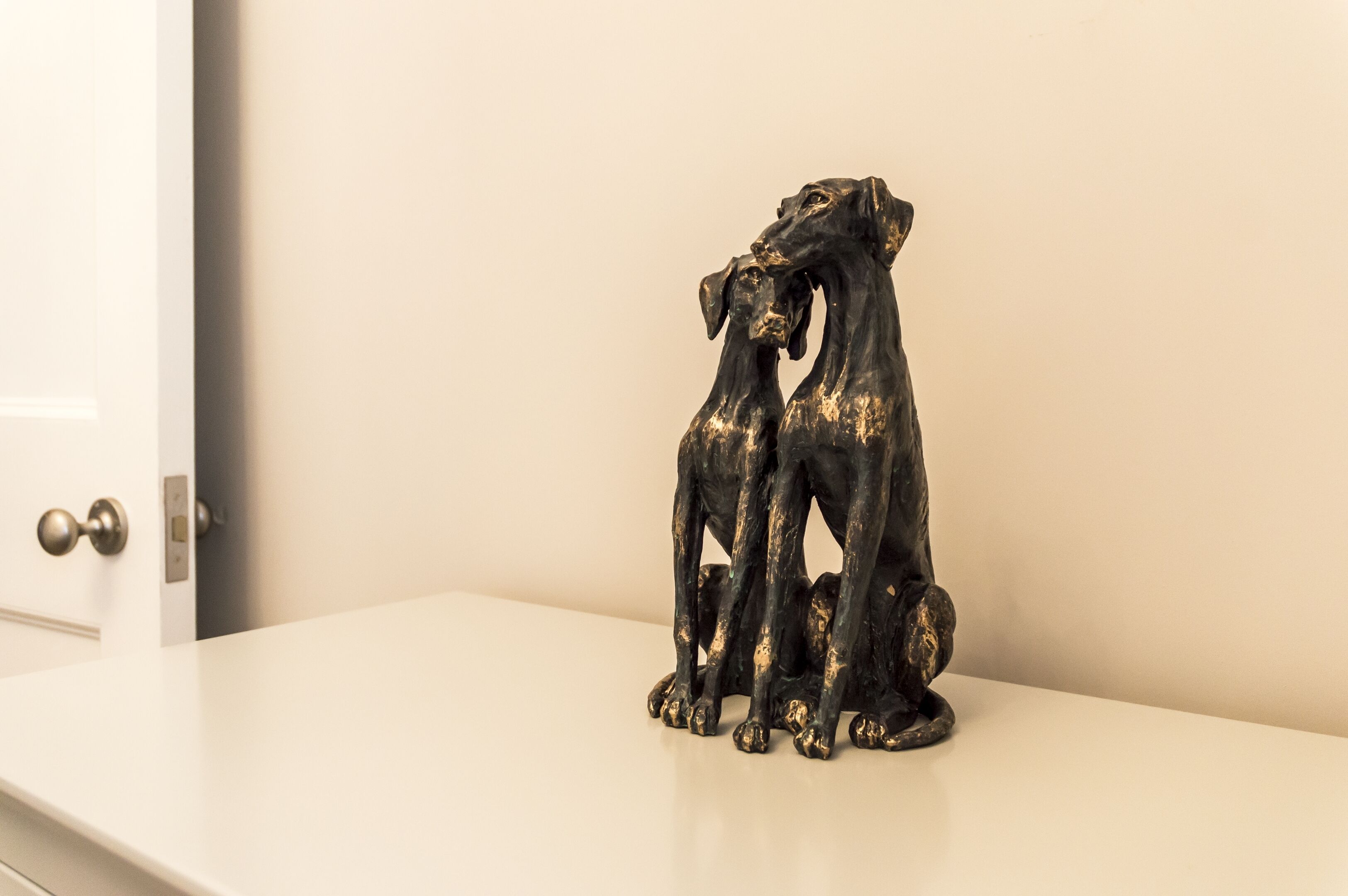 Estátua de dois cães sobre uma superfície branca.