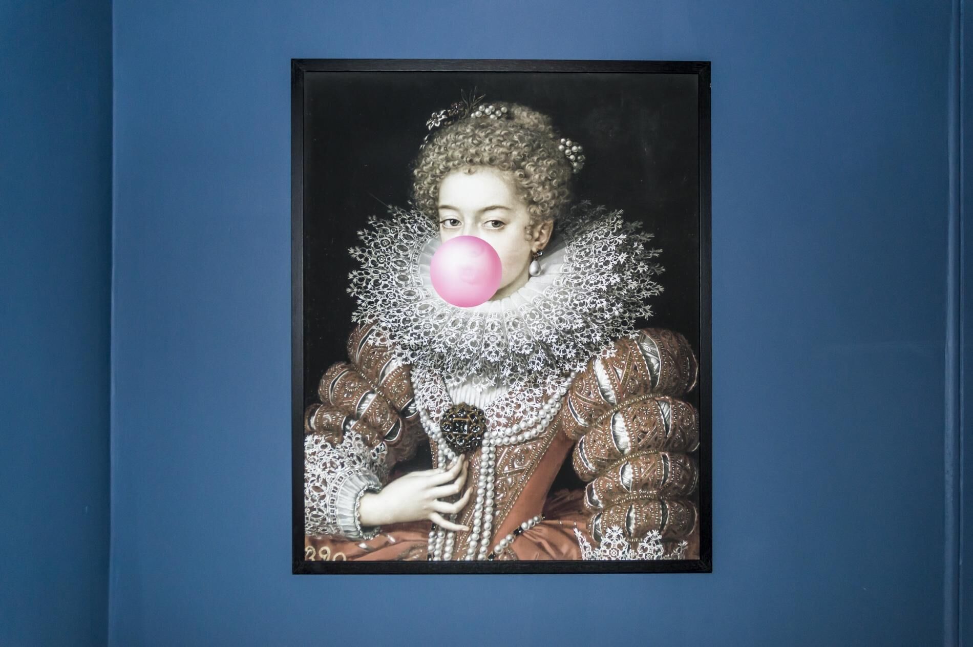 A framed portrait of a person in historical attire with a ruffled collar and elaborate jewelry.