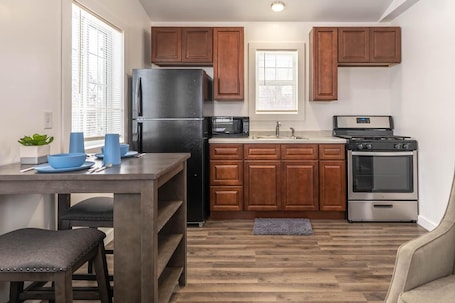A kitchen with wooden cabinets, a black refrigerator, a microwave, a stove, and a sink.