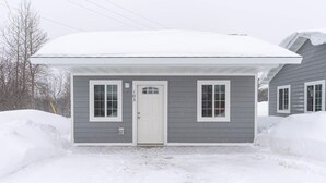 A single-story house with a white door, two windows on the front, and a covered porch.