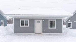 A two-story house with a gray exterior and white trim. - Explore Keweenaw - 2 Bedroom Cottage (Calumet)
