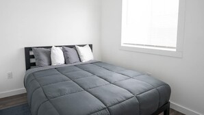 A bedroom with a bed, white walls, and a window with blinds. - Sparkling Clean! 2 Bedroom Cottage- Located in Beautiful Keweenaw (Calumet)