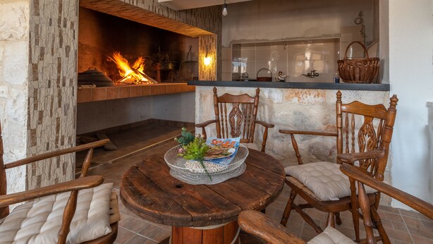 A cozy living area with a fireplace, wooden furniture, and a kitchen counter. - Eden Mediterranean house (Marina)