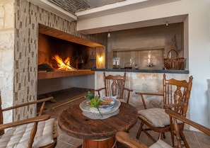 A cozy living area with a fireplace, wooden furniture, and a kitchen counter. - Eden Mediterranean house (Marina)
