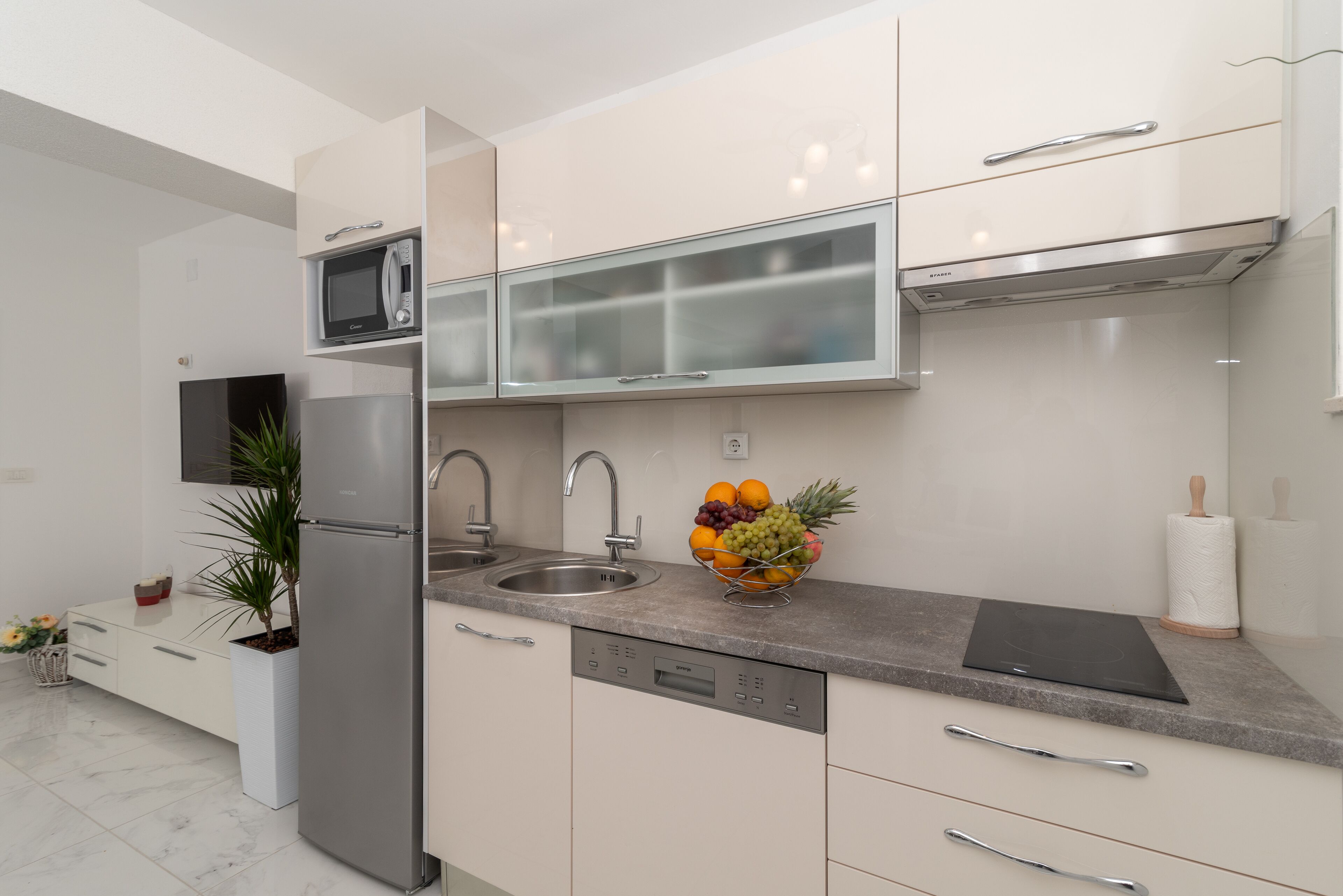 A modern kitchen with stainless steel appliances, a double sink, and a fruit bowl on the countertop.