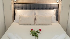 A neatly made bed with white linens, two rolled towels, and a bouquet of red roses. - Eden Mediterranean house (Marina)