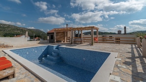 A swimming pool with steps, a wooden pergola, and a stone wall. - Eden Mediterranean house (Marina)