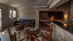A cozy living room with a fireplace, leather sofa, wooden chairs, and a round table with a decorative bowl. - Eden Mediterranean house (Marina)