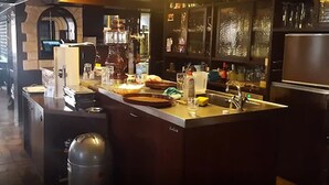 Zona de bar con mostrador, taburetes y un refrigerador.