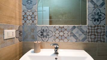 A bathroom with a white sink, a mirror, and patterned tiles on the wall.