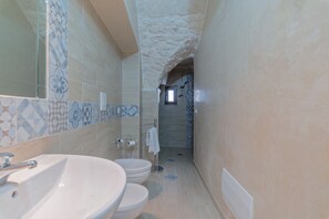 A narrow bathroom with a sink, two toilets, and a shower area. - La Bianca Suite (Ostuni)