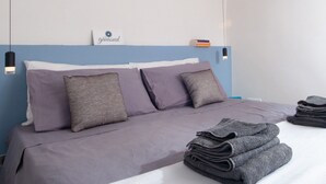 A neatly made bed with a blue headboard, two pillows, and a sign above. - Giùasud (Ostuni)