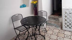 A dining area with a round table and four chairs, a vase with yellow flowers, and a decorative blue vase on the wall. - Giùasud (Ostuni)