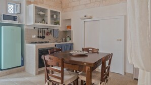 Een kleine keuken met een eettafel, stoelen en basisapparatuur.