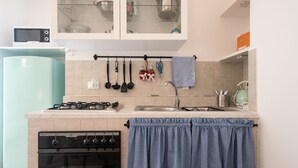 Een keuken met een kookplaat, oven, spoelbak en kastjes.