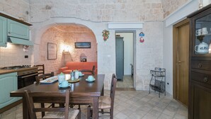 Una cocina rústica con pared de piedra, armarios de madera y una mesa de comedor lista para cuatro comensales.