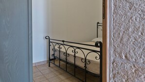 Una habitación pequeña con una cama individual, estructura metálica y colchón sencillo.