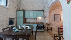 Una cocina rústica con armarios azul claro, una mesa de comedor con sillas y piso de baldosas.