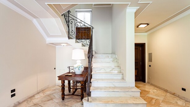 Una escalera de mármol con una mesa de madera y una lámpara al pie.