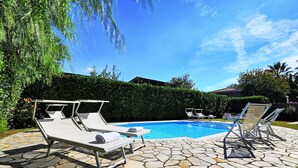 Una piscina con sillas de descanso y un patio de piedra.