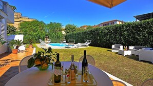 Zona junto a la piscina con mesa lista para comer, asientos exteriores y vista al agua.
